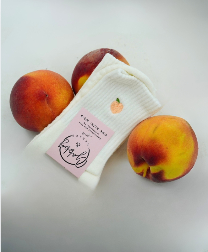 a pair of white grip socks sits next to peaches