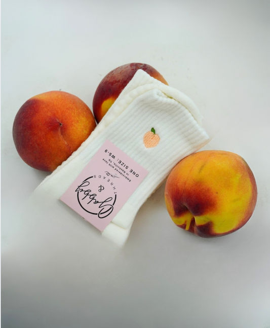 a pair of white grip socks sits next to peaches