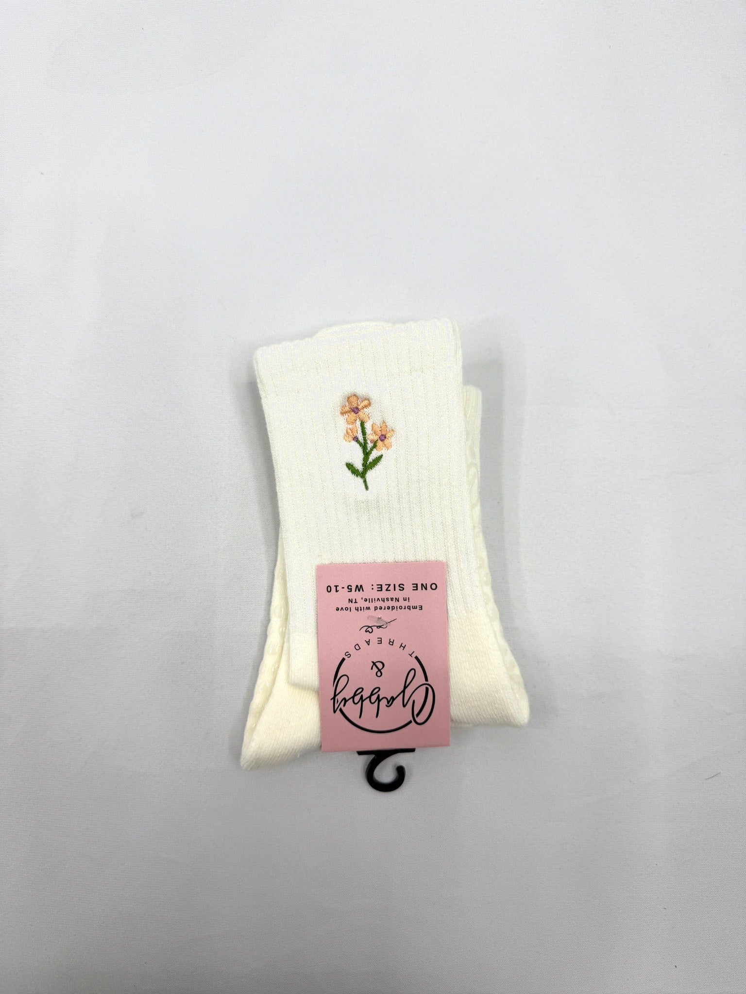 a pair of white grip socks with a floral design embroidered on them