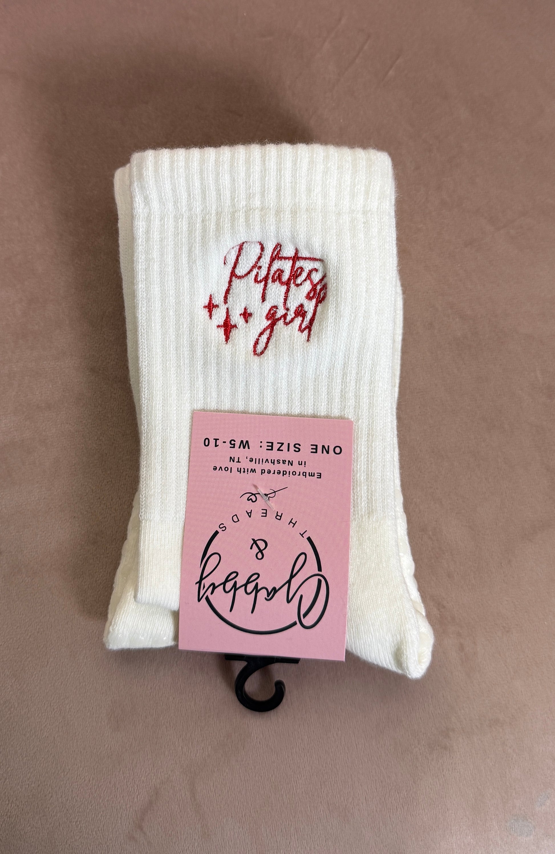 a pair of white grip socks with the words "pilates girl" embroidered on them 