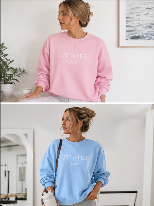 Two women wearing pink and blue 'PILATES girl' sweatshirts in a home setting.