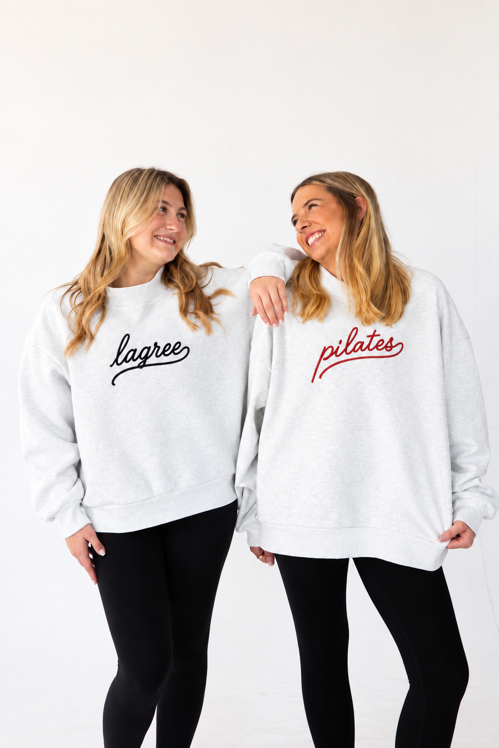 two models wearing heather gray mock necks. One mockneck is embroidered with the word "lagree" in script and one is embroidered with the word "pilates" in script