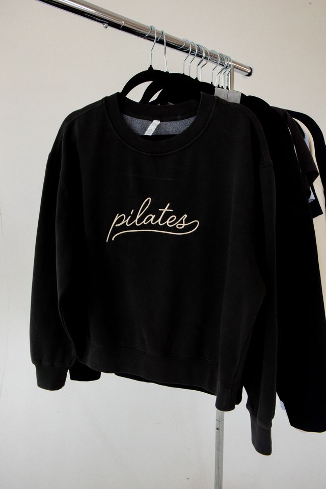 embroidered black crewneck with the word pilates in script