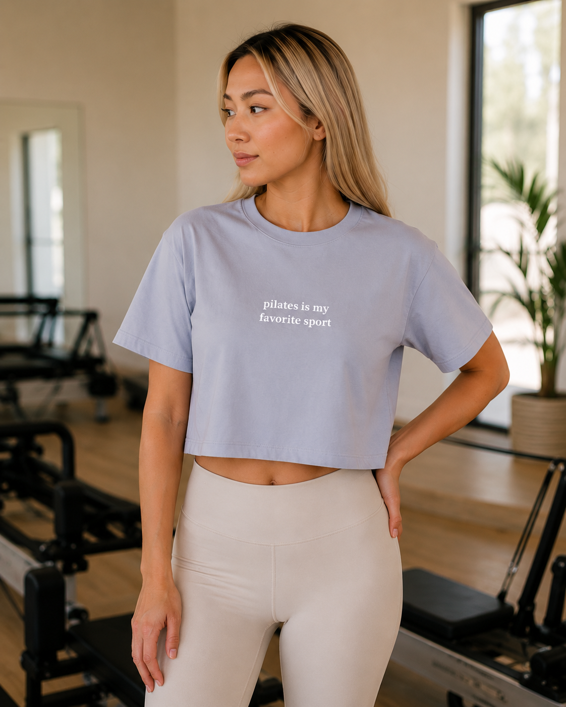 a women is in a pilates studio wearing a cropped tshirt that says "pilates is my favorite sport"