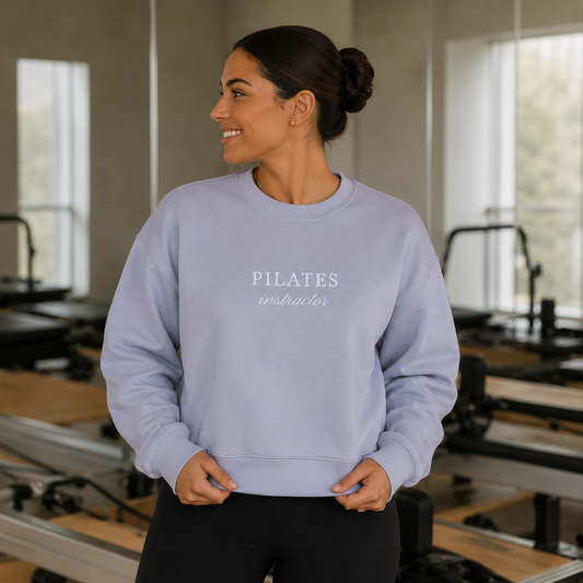 a woman is in a pilates studio wearing an embroidered crewneck that says pilates instructor on it