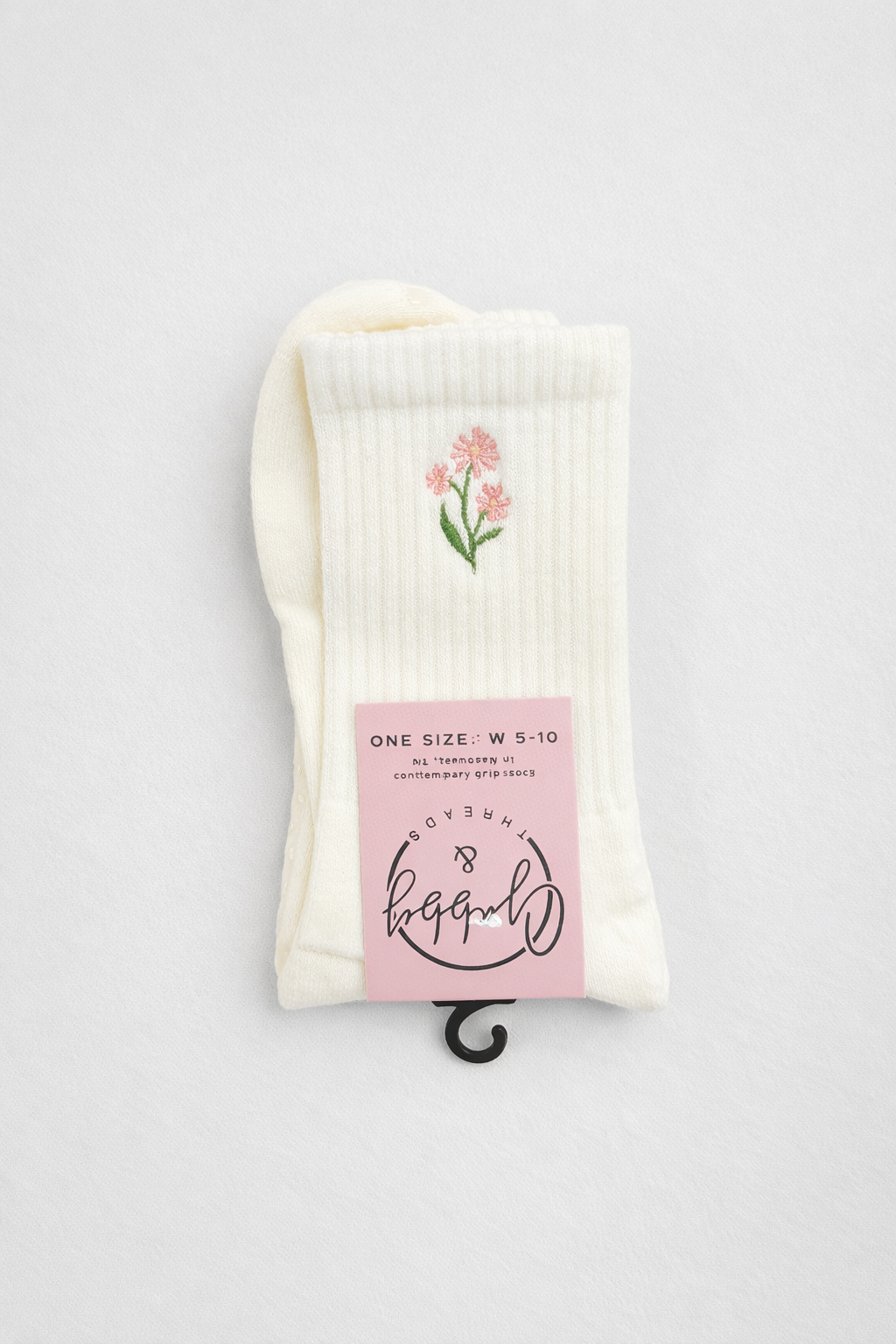 a pair of white grip socks with a pink embroidered flower 