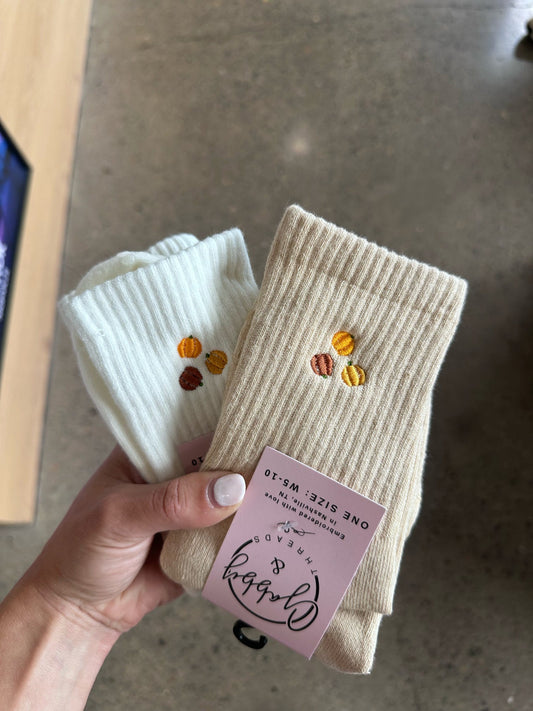 beige and white embroidered grip socks with pumpkins on them