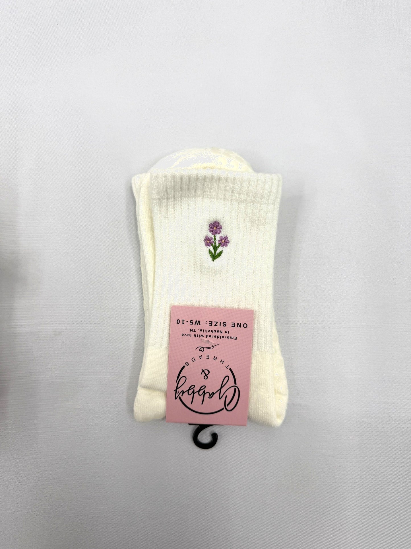 White socks with a purple flower design on a gray background