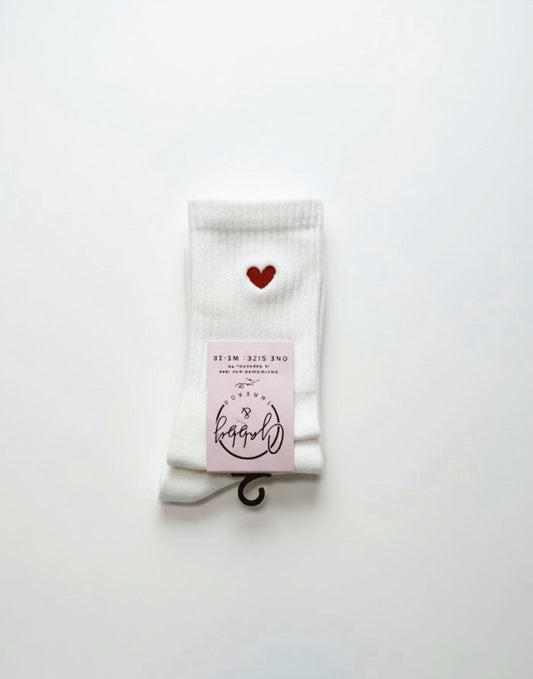 a pair of white grip socks with an embroidered red heart on them