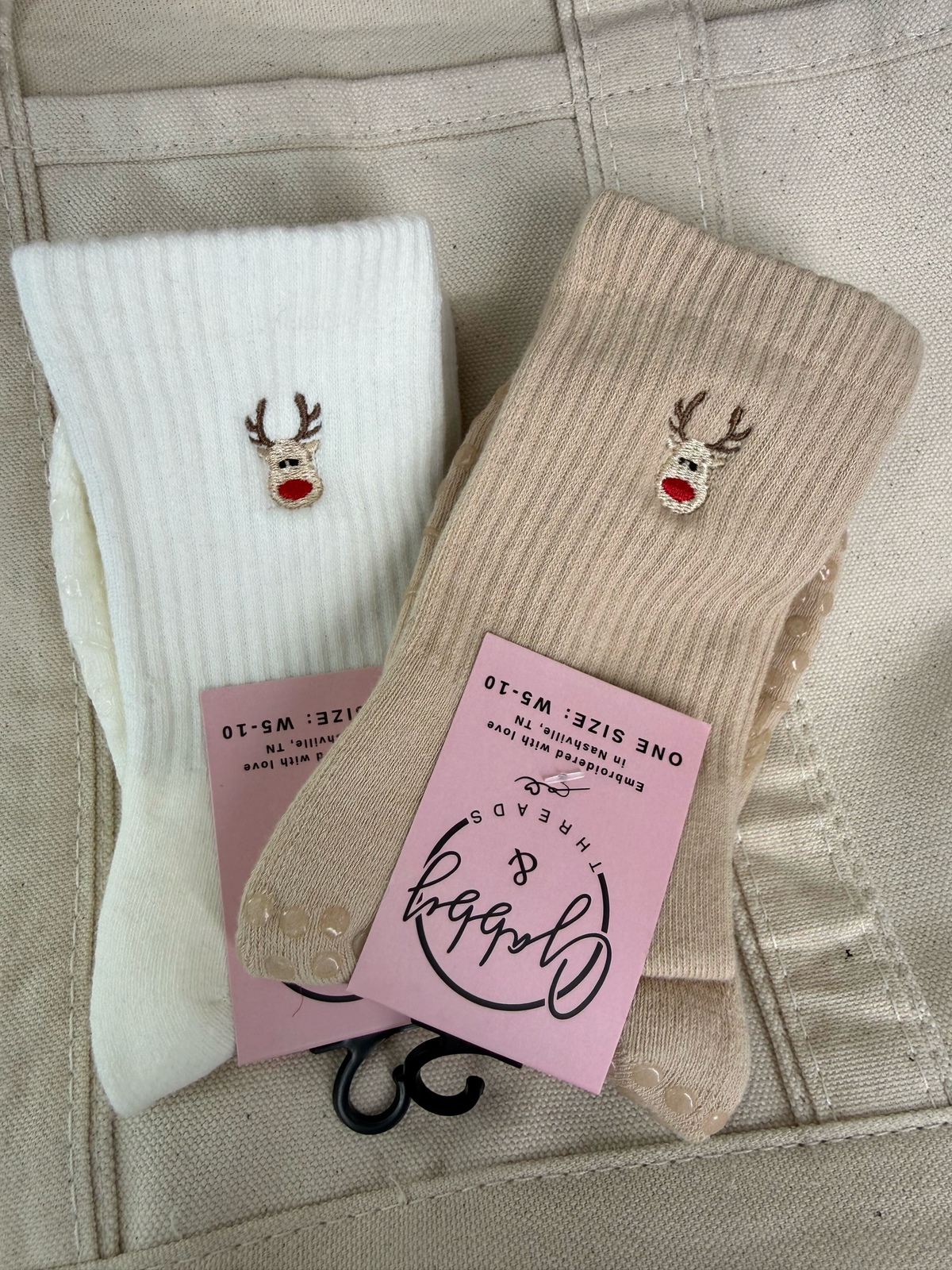 a pair of white and tan socks with an embroidered reindeer on them