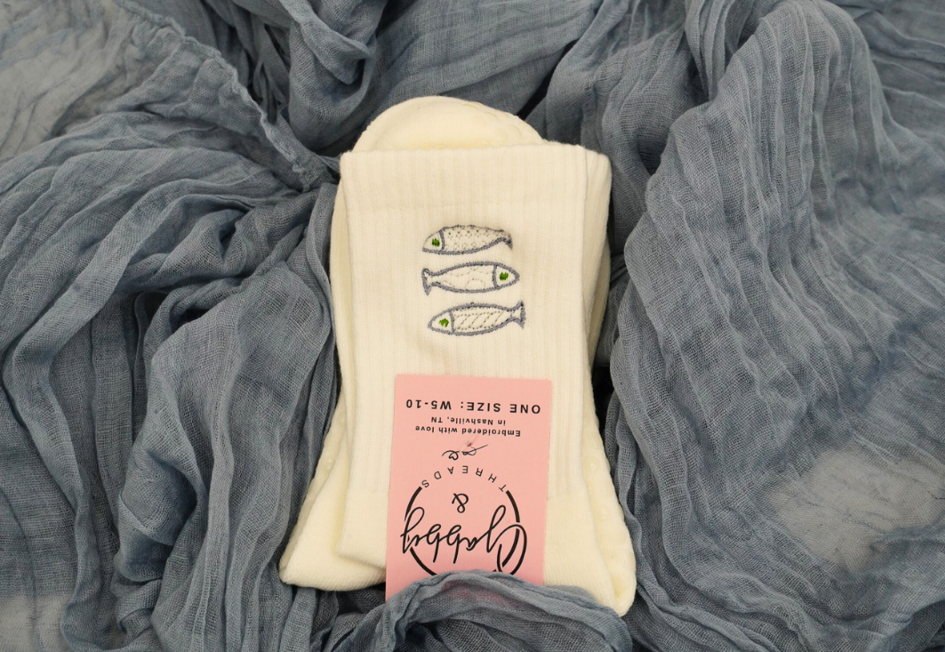 a pair of white grip socks with sardines embroidered on them