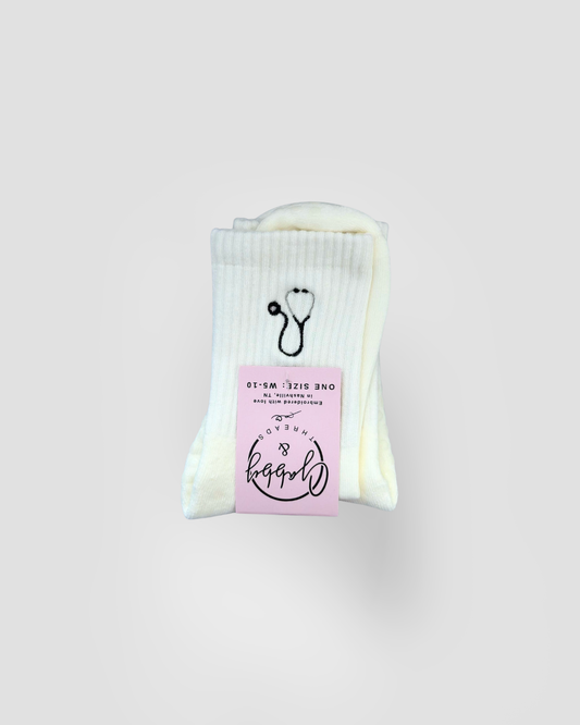 a pair of white grip socks with an embroidered stethoscope on them