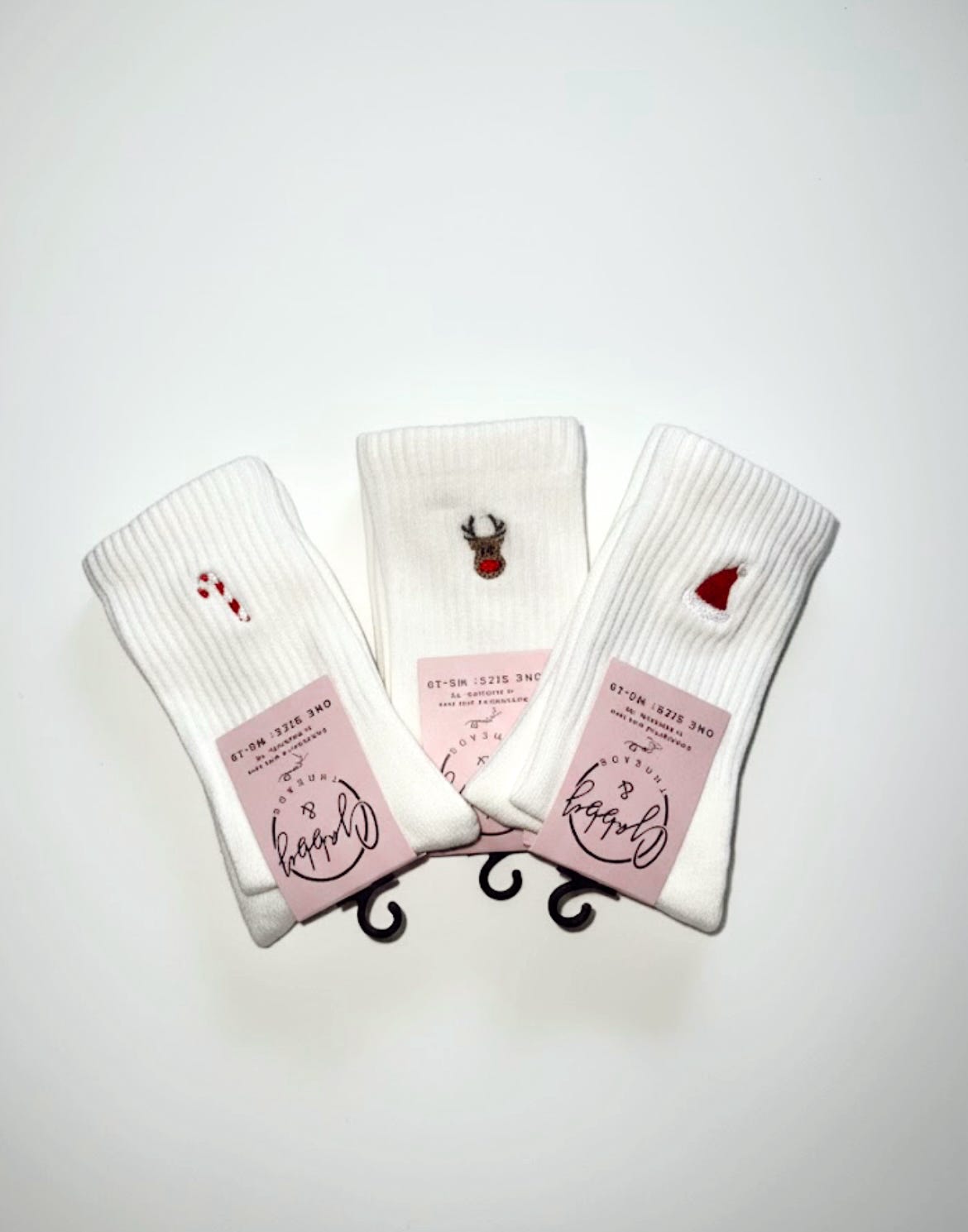 three pairs of grip socks with embroidered holiday icons (santa hat, candy cane and a reindeer)