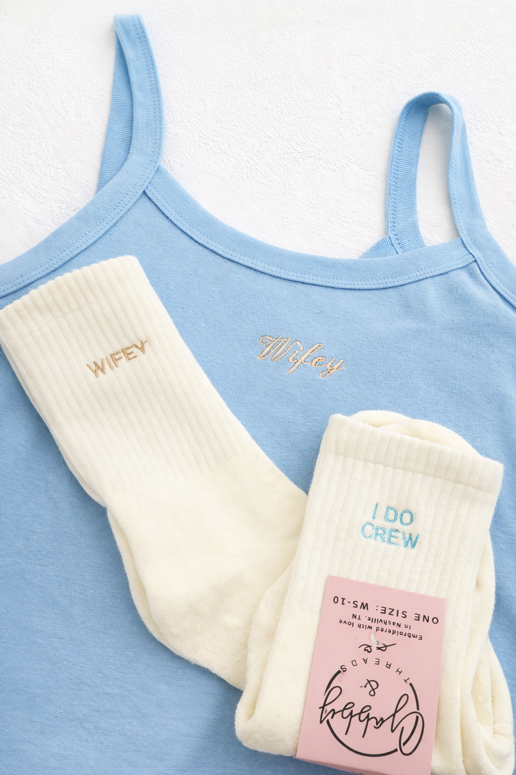 Light blue tank top with 'Wifey' and 'I Do Crew' socks on a white background