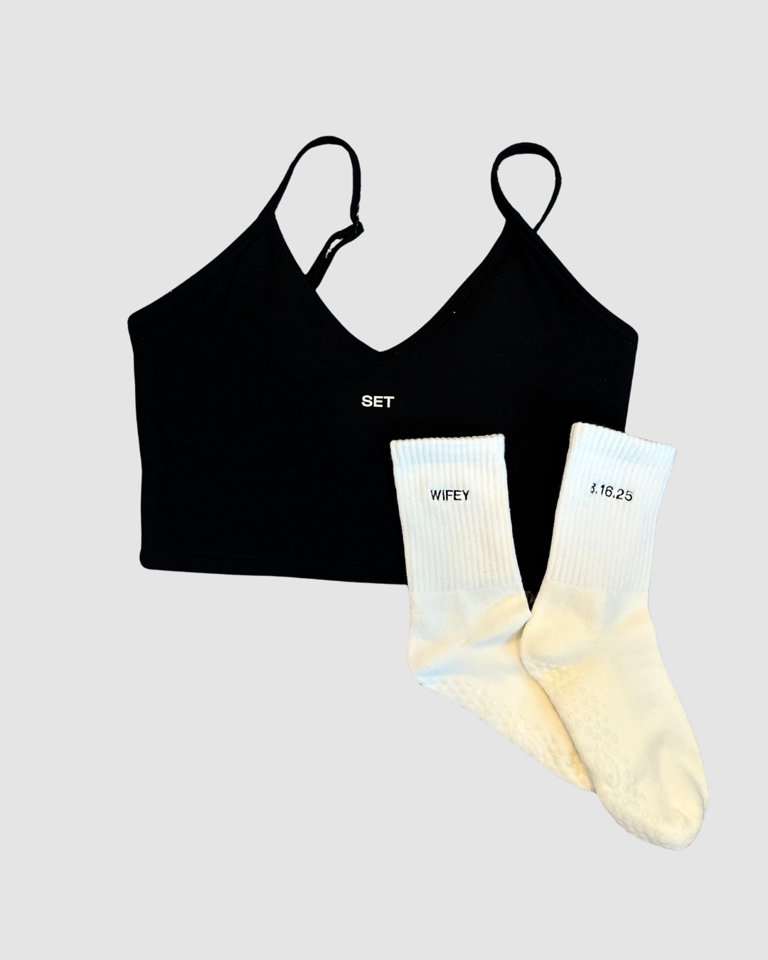 a black set active sports bra with a pair of white grip socks with a wedding date and the word "wifey" embroidered on them