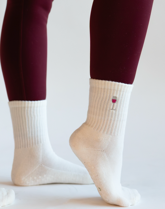 a person is wearing a pair of white grip socks with an embroidered wine glass on them