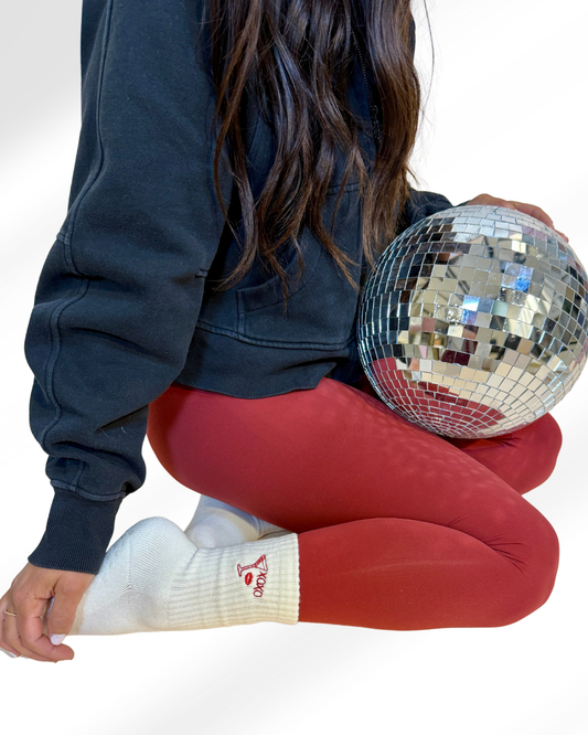 a person is wearing a pair of white grip socks that say xoxo with a martini and lips with red leggings and a disco ball in their lap