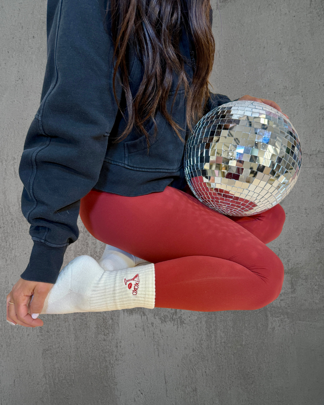 a person is wearing a pair of white grip socks that say xoxo with a martini and lips with red leggings and a disco ball in their lap