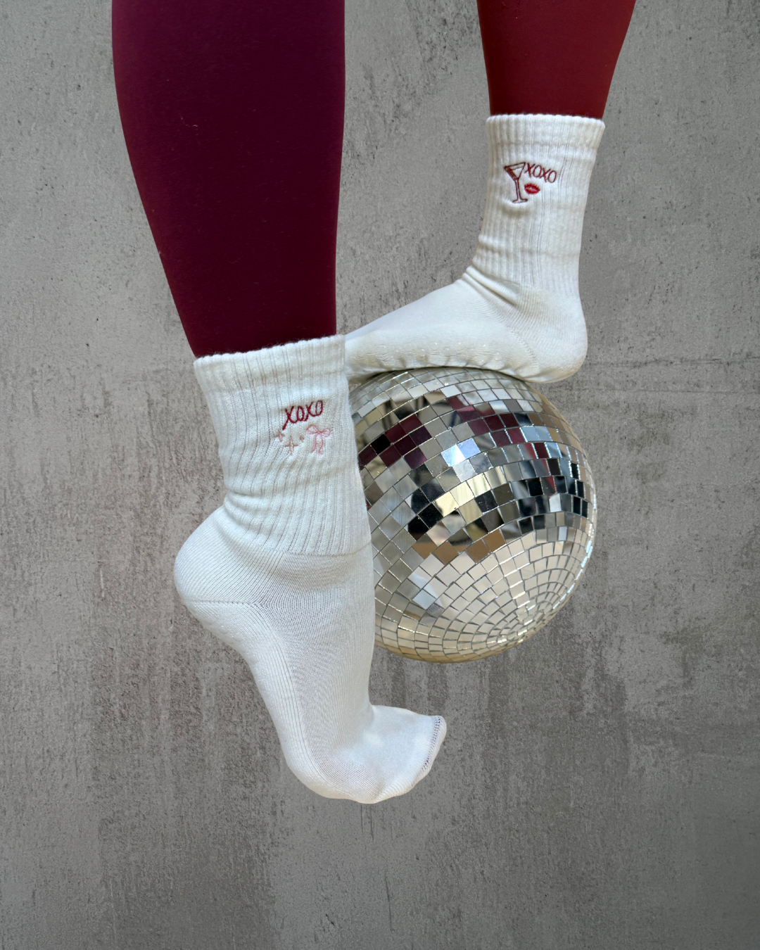 Two pairs of Valentine's day themed grip socks on top of a disco ball